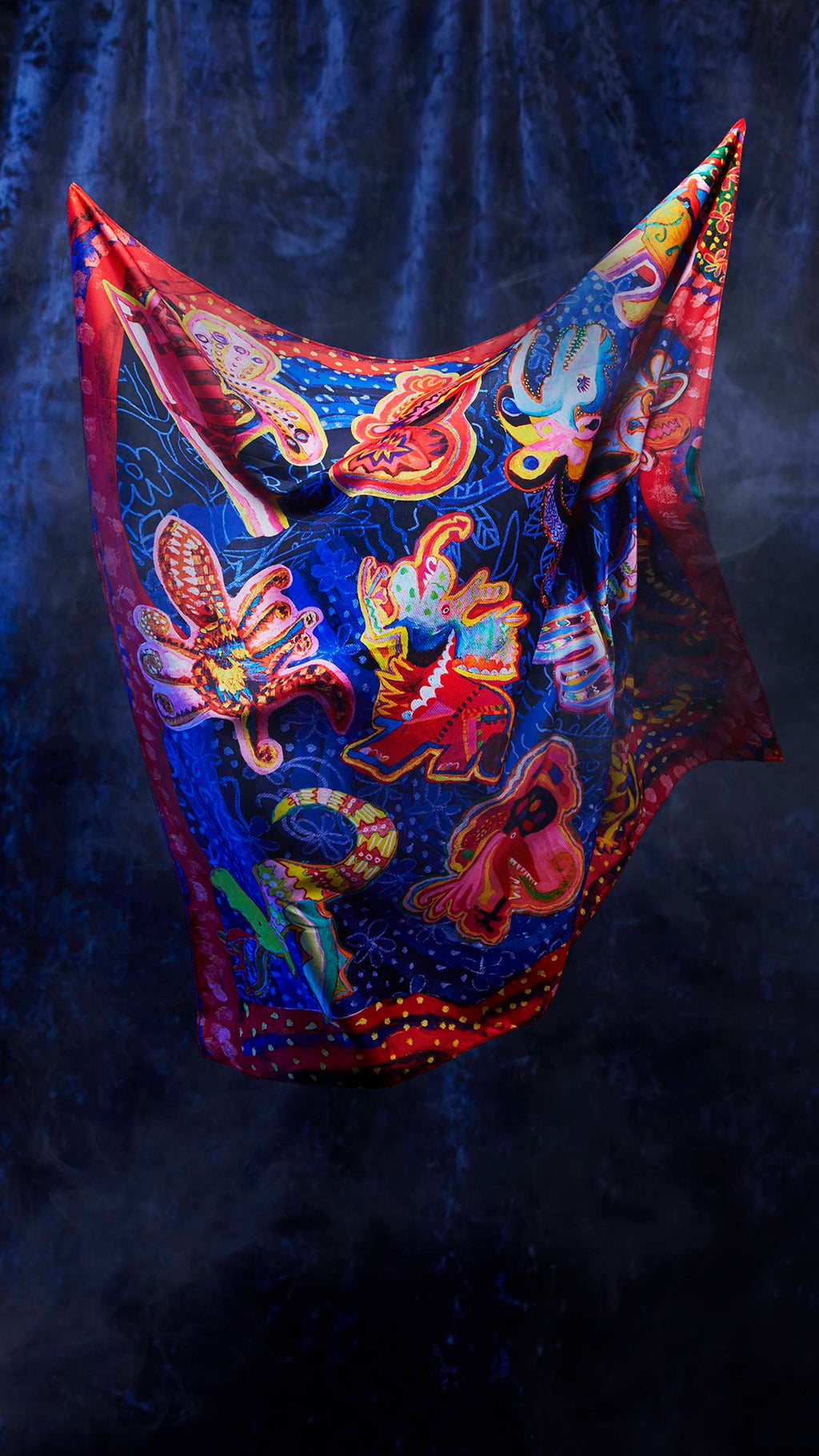 The image shows the Fantasy Animals knot wrap being suspended from the two upper corners, seemingly floating as if by magic. There is a dark, velvet background.